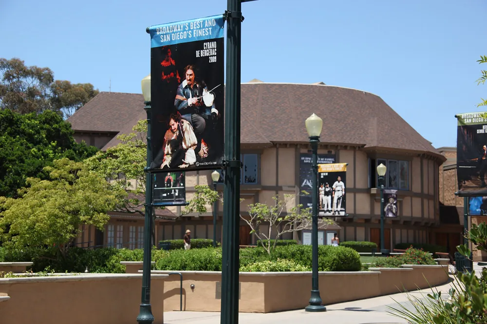 The Old Globe Theatre building in Balboa Park with show banners on lamp posts in front