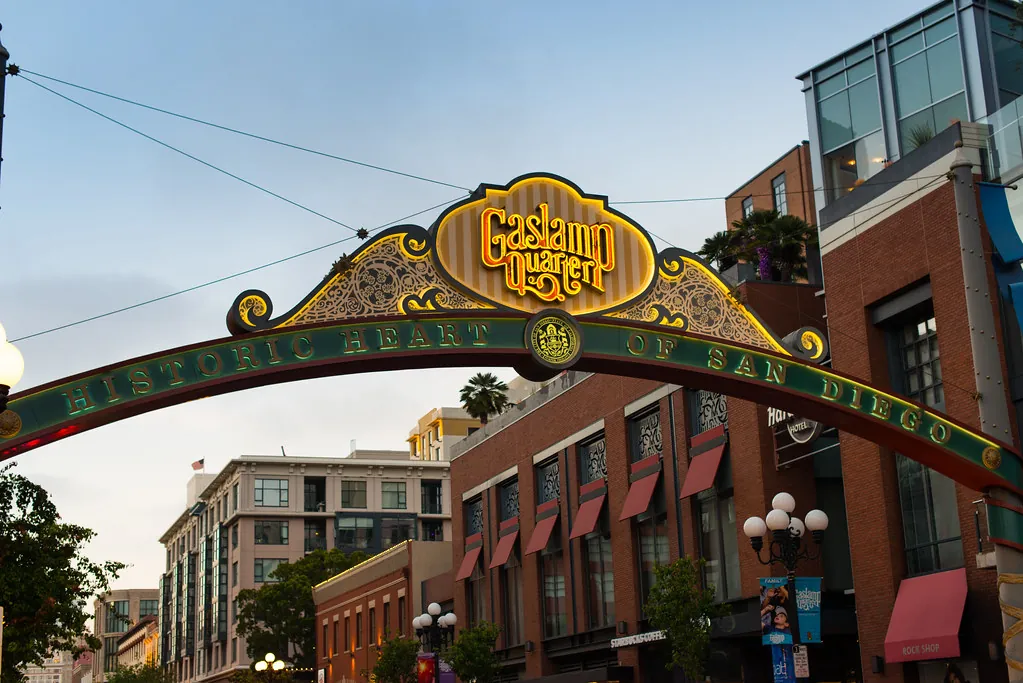 The lit-up Gaslamp Quarter archway sign over Fifth Avenue in downtown San Diego at dusk